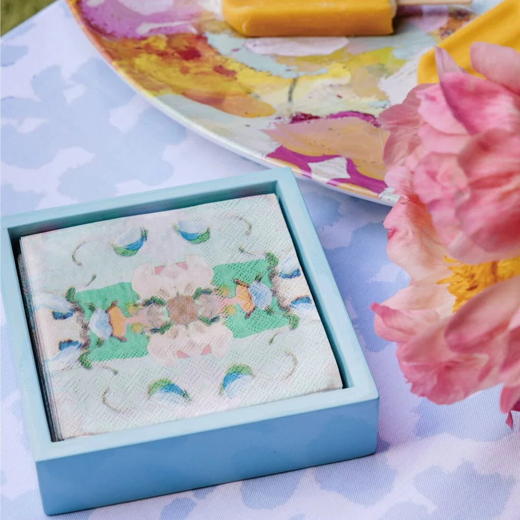 Napkin Holder - Light Blue Bamboo - Cocktail- blight blue napkin holder has colorful napkins inside it and is sitting on a purple blue table with a colorful plate and flowers