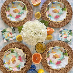 Plates - Paper - Cocktail - Park Avenue- picture is of 4 colorful park avenue paper plates on 4 brown wicker chargers as well as a bouquet of flowers on the table 
