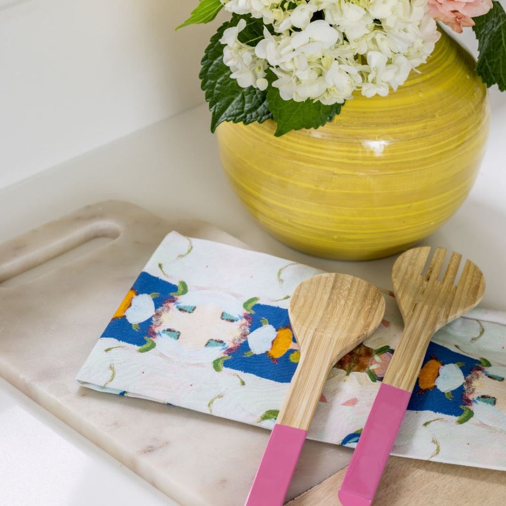Tea Towel - Monets Garden - Navy- the tea towel with colorful design is sitting with two wooden kitchen spoons near a yellow vase with flowers on a cutting board