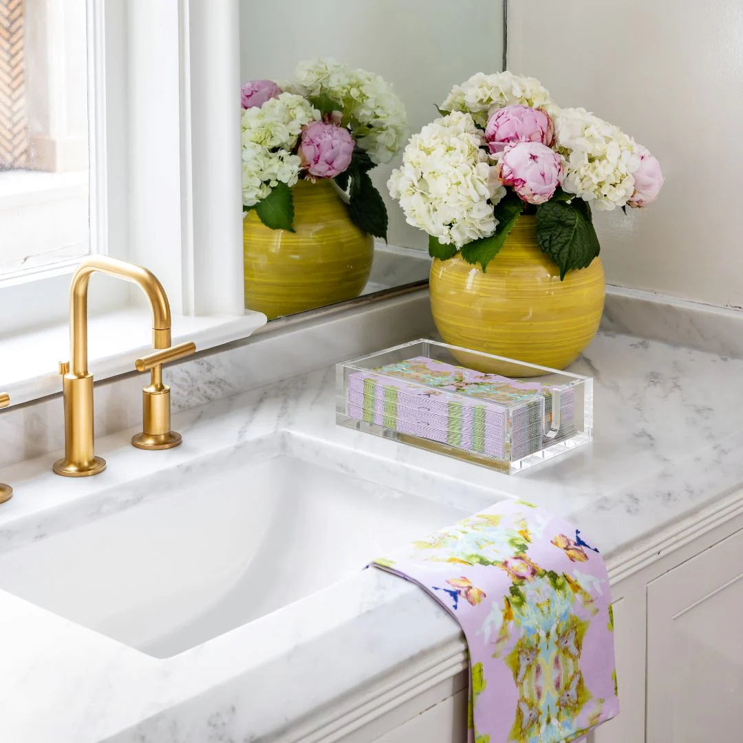 Tea Towel - Stained Glass Lavender- this picture is of the colorful tea towel resting on a sink also in the picture are colorful towel napkins and a yellow vase full of flowers 