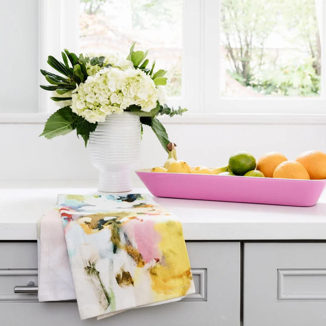 Tea Towel - Under The Sea- this is a picture of the colorful under the sea design tea towel resting on a kitchen counter top with a vase of flowers and a display of fruit 