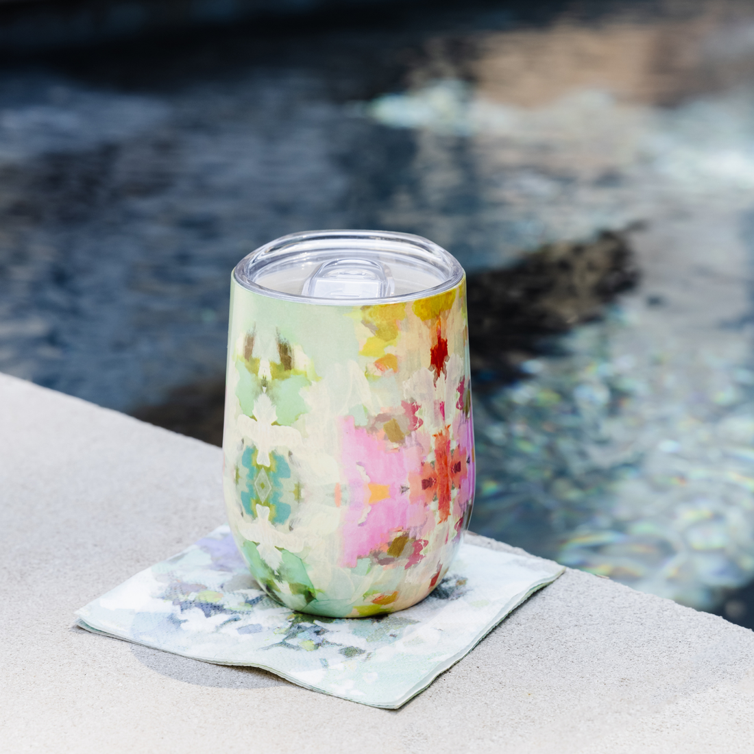 Tumbler - Stemless Wine - Giverny-this is a picture of the wine tumbler in the giverny colorful design sitting on a napkin by the pool