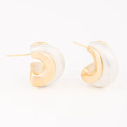 Pair of gold and white hoop earrings on a light beige background