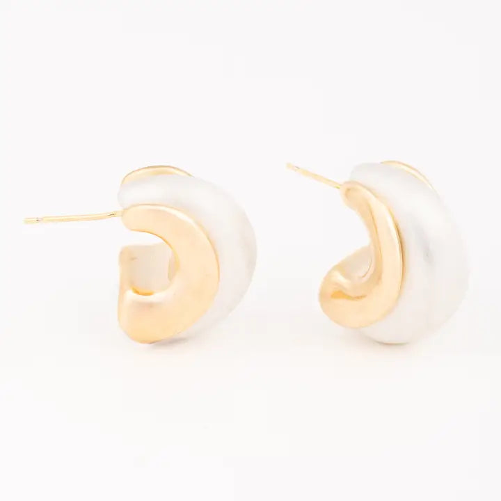 Pair of gold and white hoop earrings on a light beige background
