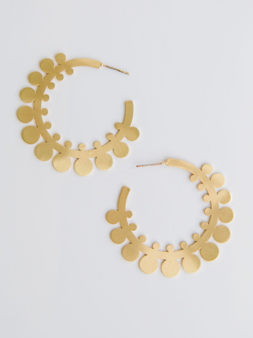 Gold hoop earrings with floral design on a light gray background