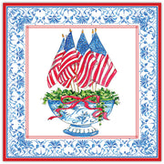 Decorative Roseanne Beck Paper Placemat with American flags, a blue urn, and floral arrangement on a decorative border.