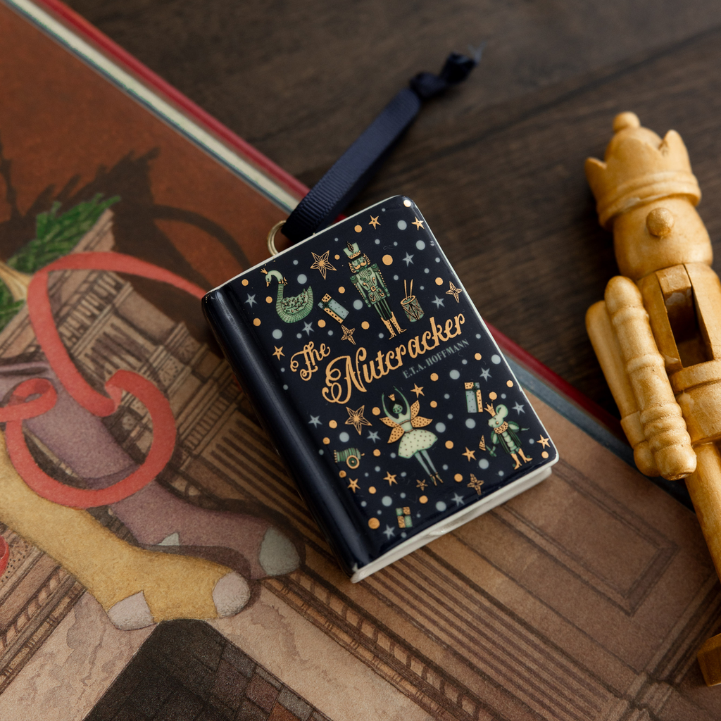 Seasonal - Ceramic  Ornament - Book shape- The Nutcracker - Laying on a table with other Christmas decorations 