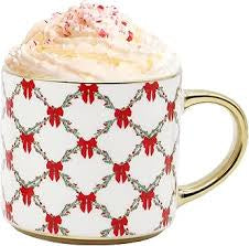 Mug with red bow pattern filled with a hot beverage and whipped cream.