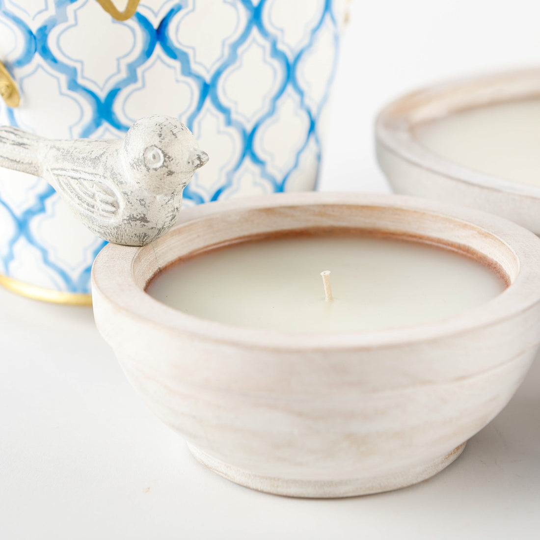 Candle in a wooden bowl with decorative elements in the background