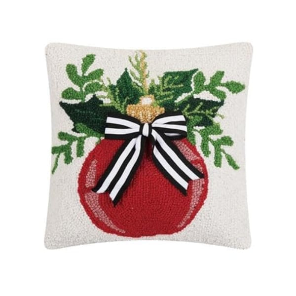 Decorative pillow with a red ornament, green leaves, and a black and white bow on a white background.