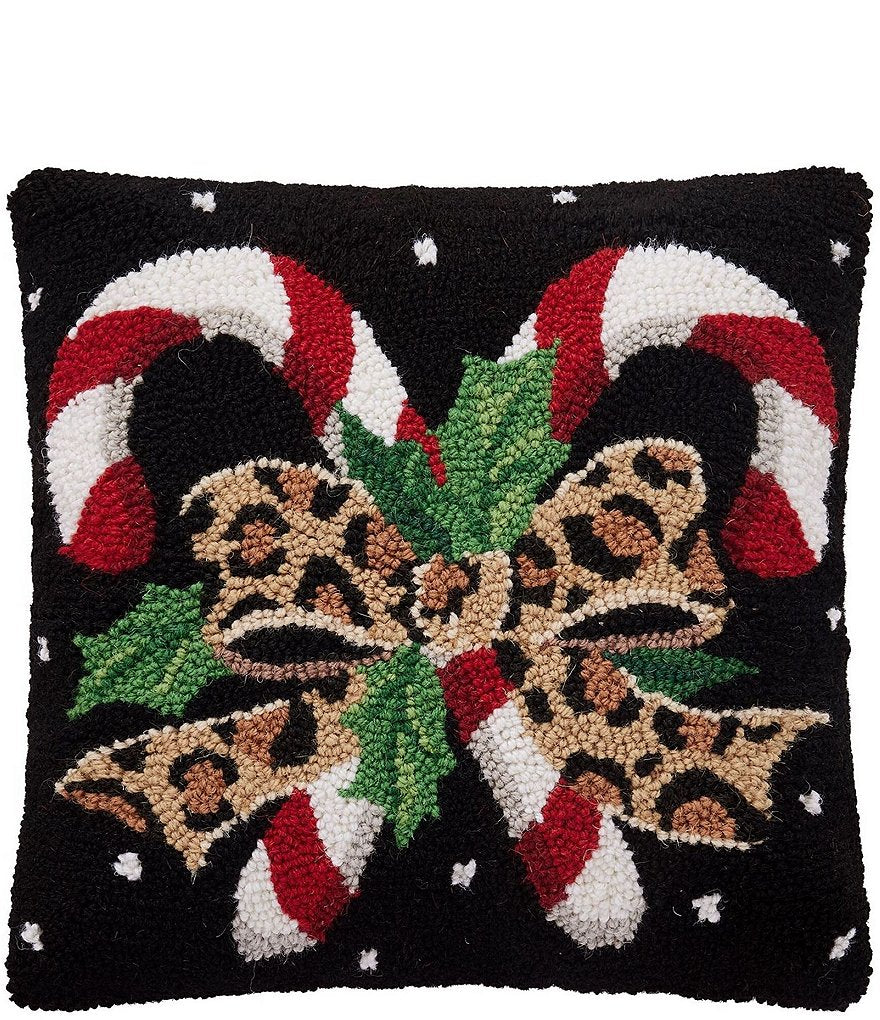 Decorative pillow with candy canes, leopard print bows, and Christmas elements on a black background.