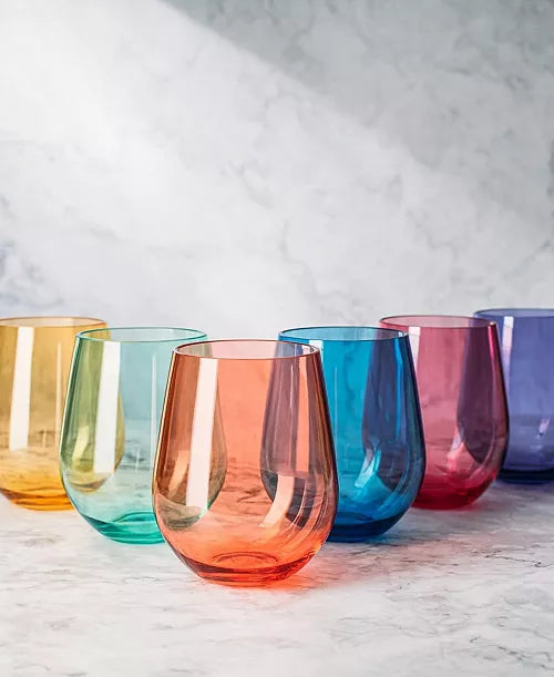 Set of colorful glass tumblers on a marble surface with a light gray background