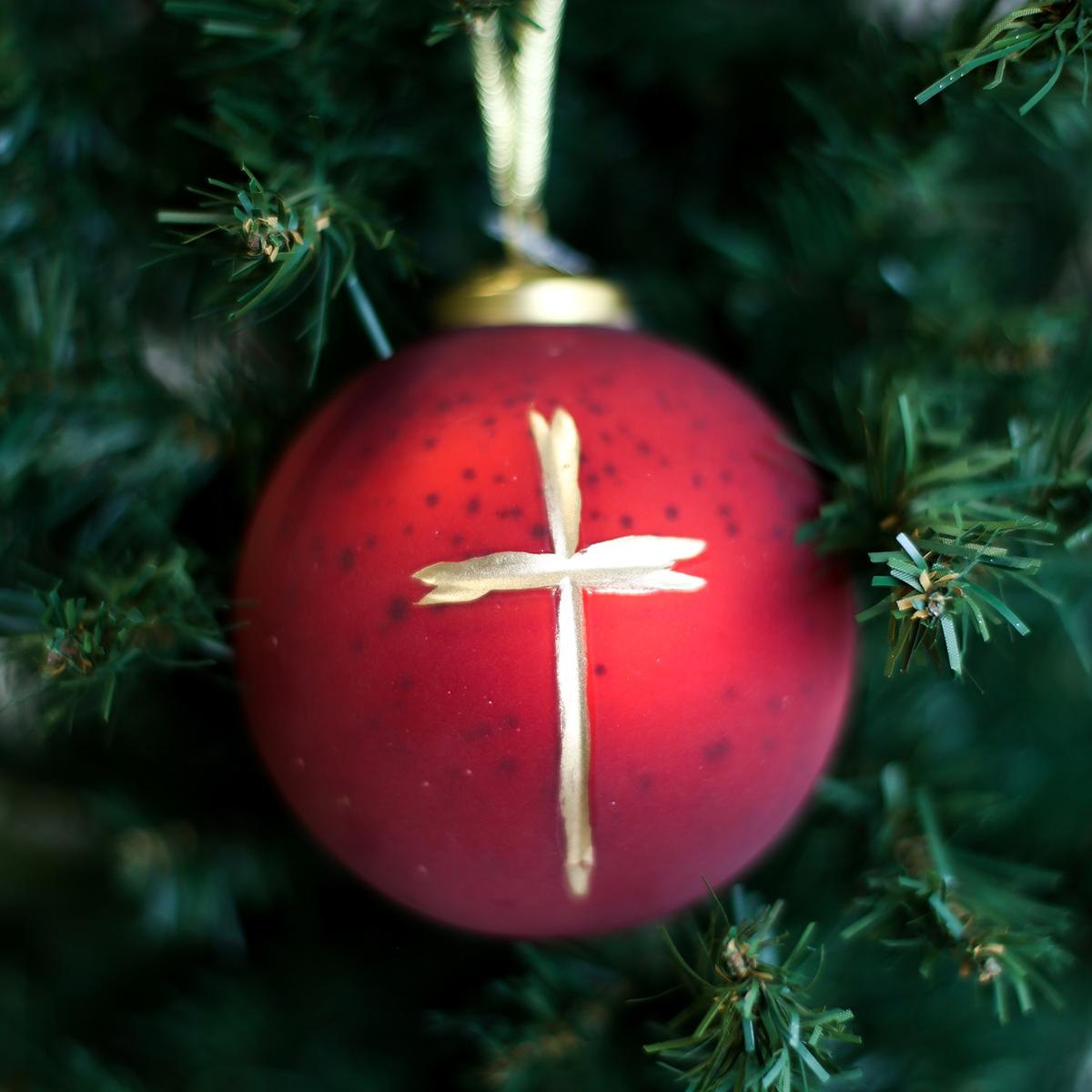 Red ornament with gold cross on a tree