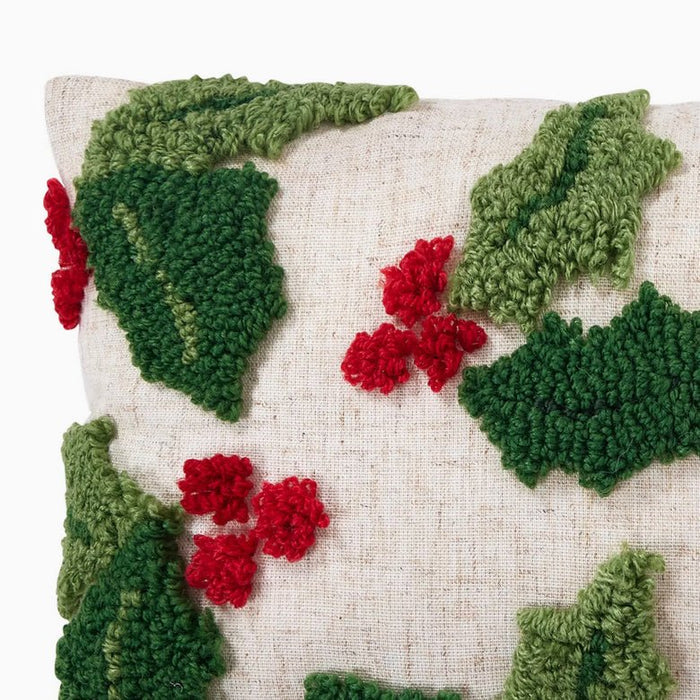 Decorative pillow with knitted green leaves and red berries on a beige background