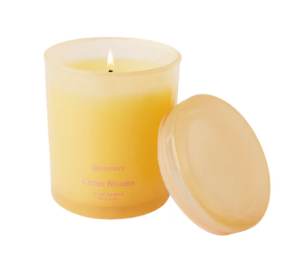 Aromatique Citrus Candle with a lit wick and a lid on a white background