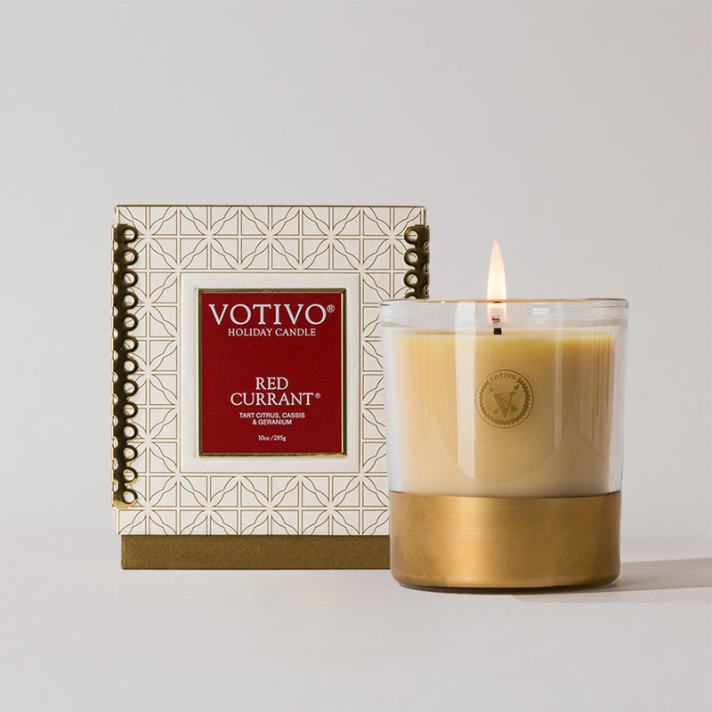 Votivo Red Currant candle with a gold base and packaging on a light gray background