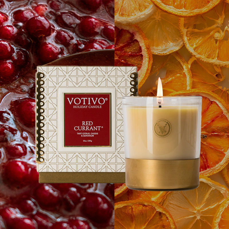 Votivo Red Currant candle with packaging against a background of cranberries and orange slices.