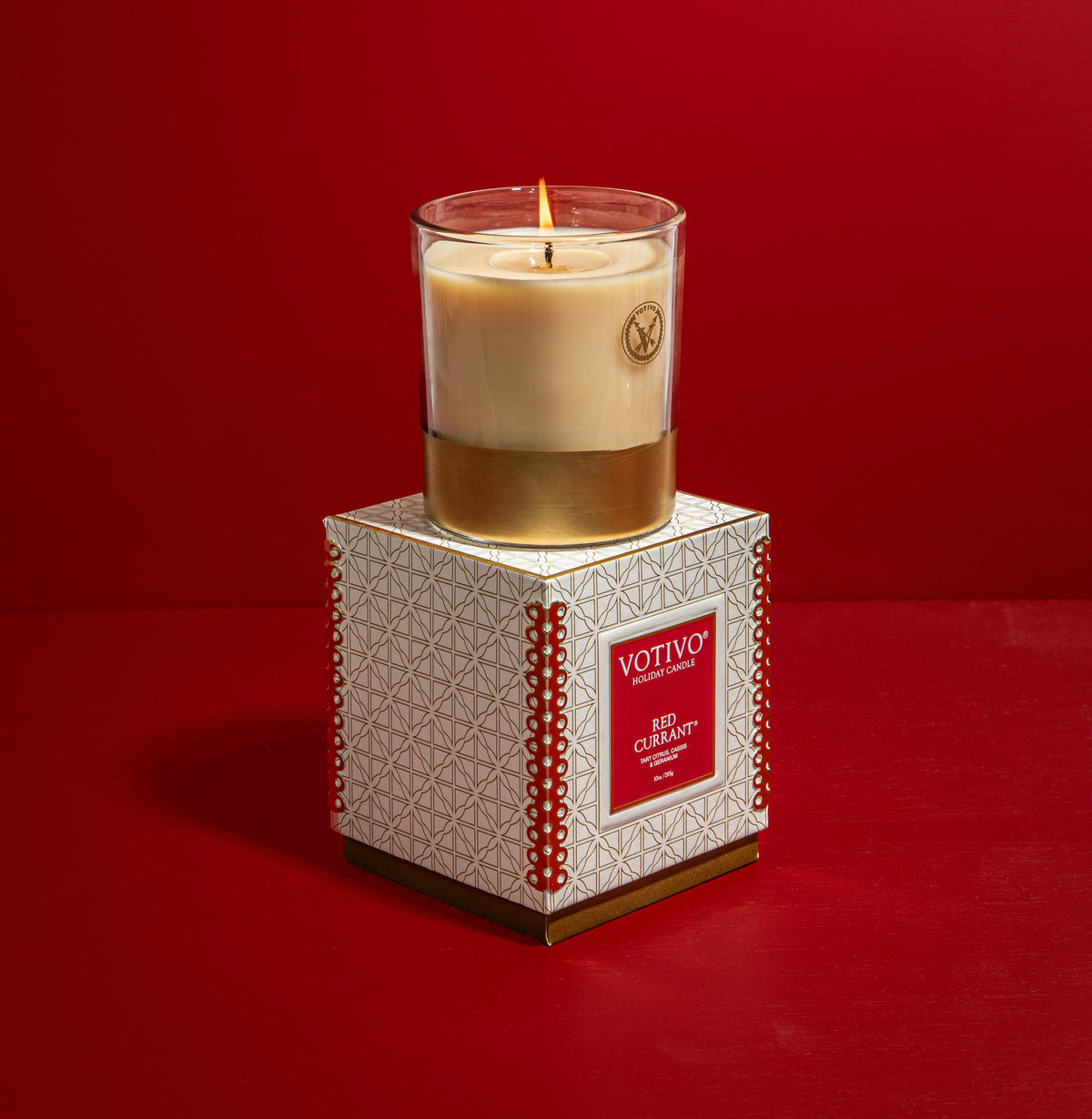 Votivo candle on a decorative box against a red background