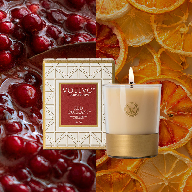 Votivo Red Currant candle with packaging against a background of cranberries and orange slices