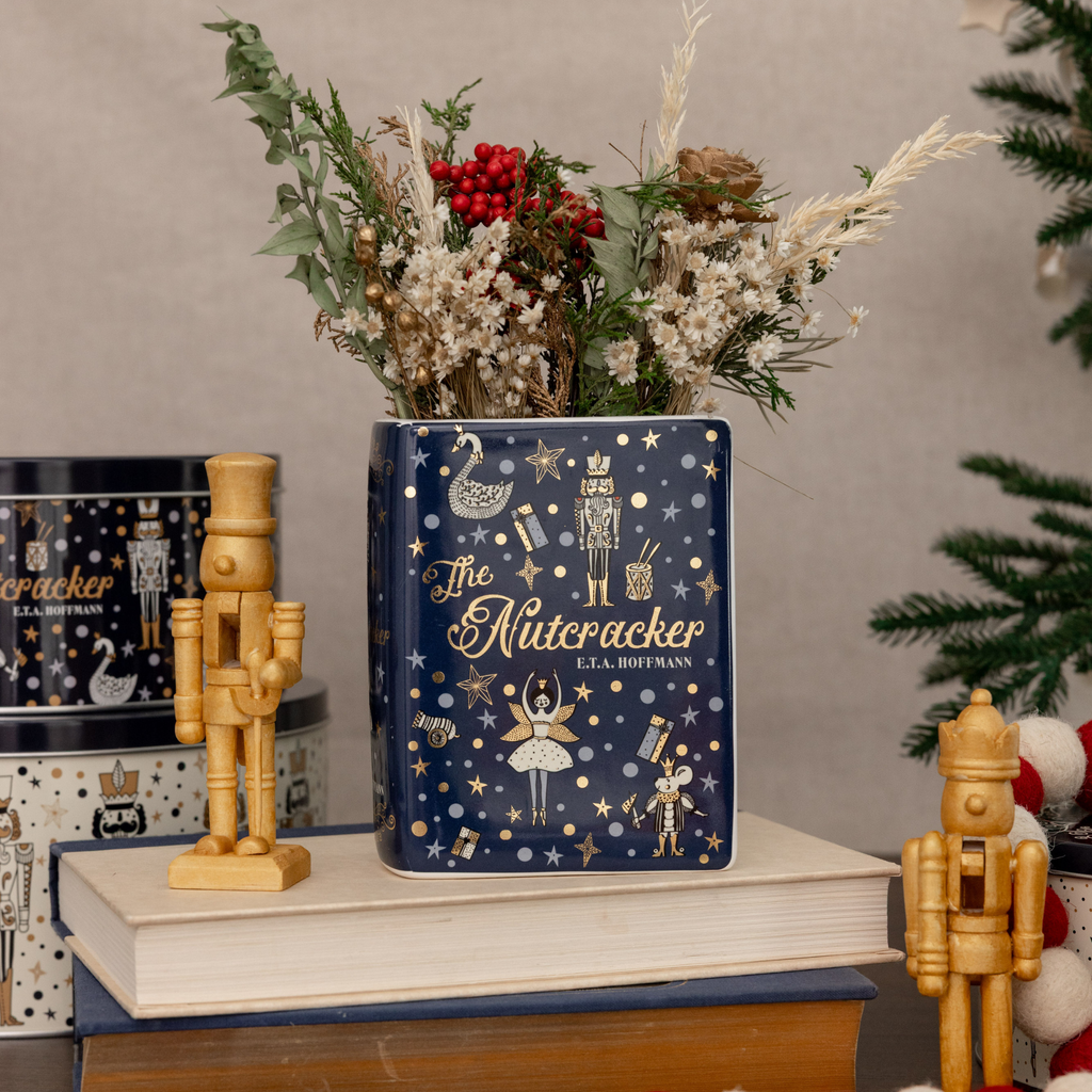 Decorative vase with 'The Nutcracker' design, surrounded by Christmas decorations.