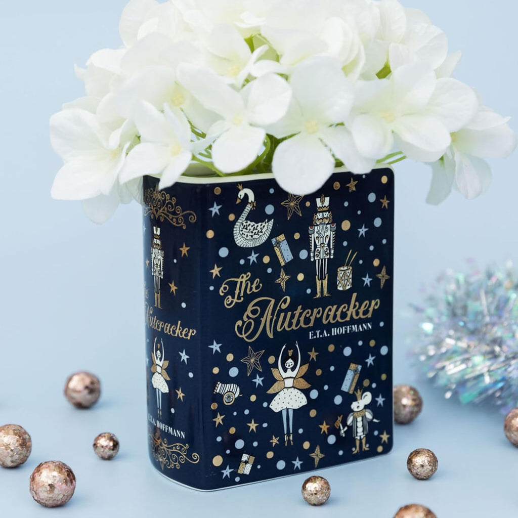 Decorative tin canister with 'The Nutcracker' design featuring white flowers on a light blue background.