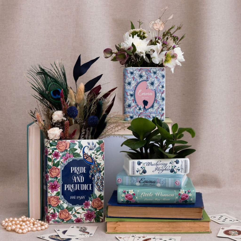 Decorative books with floral designs and a vase of flowers on a beige background
