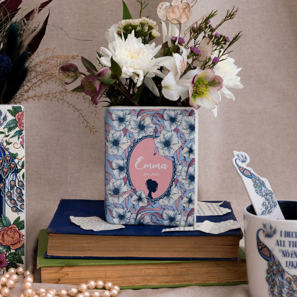 Decorative book with floral design and 'Emma' text, surrounded by flowers and a mug.