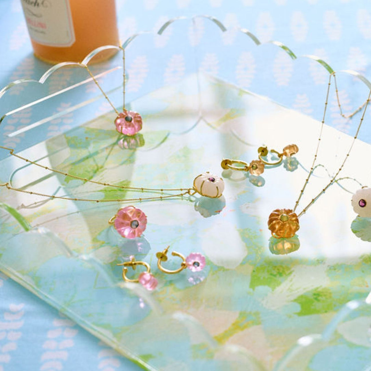 Jewelry set with necklaces and earrings on a decorative tray with a blue and green pattern.