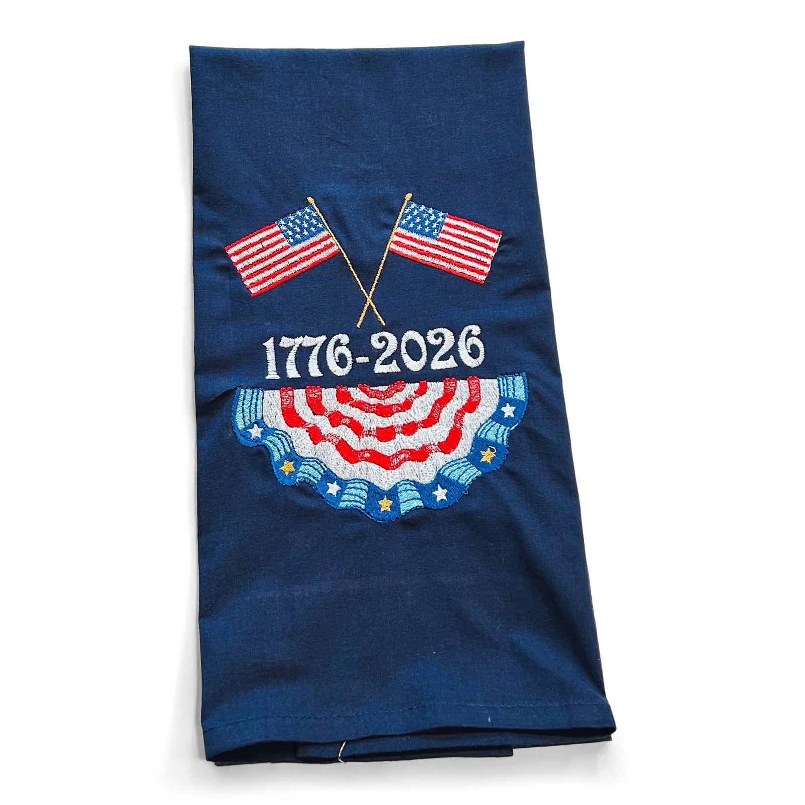 Folded blue tea towel with American flags and '1776-2026' text on a white background