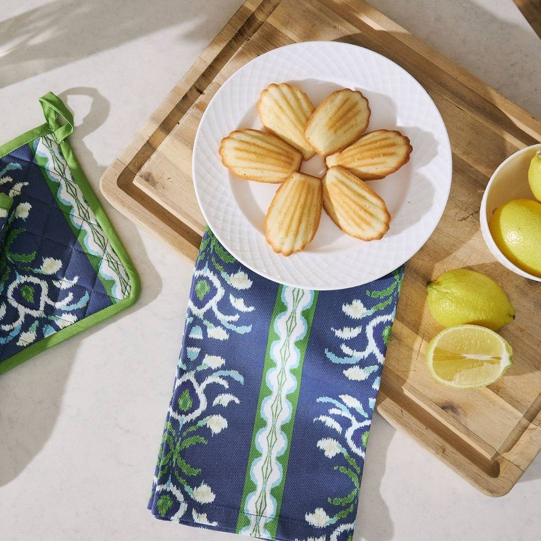 Blue patterned towel on a table with a plate of cookies and lemons.