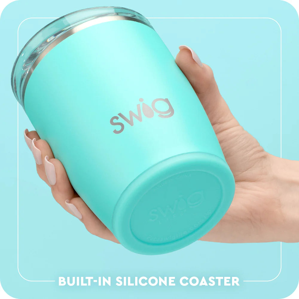 Turquoise tumbler with 'Swig' branding held by a hand against a light blue background