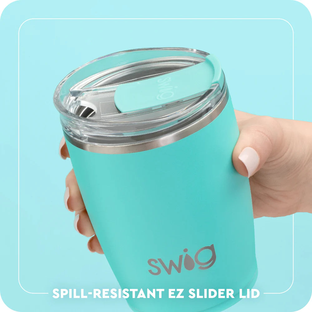 Turquoise Swig tumbler with spill-resistant EZ slider lid held by a hand on a light blue background