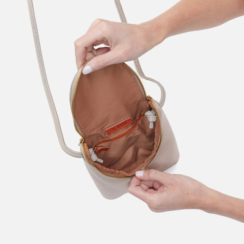 Small beige handbag with a zipper being opened, showing an orange interior.