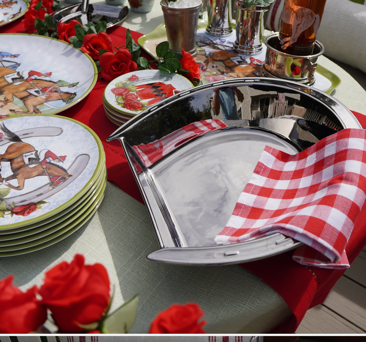 Table setting with decorative plates, silver horse shoe shaped platter  and red roses.