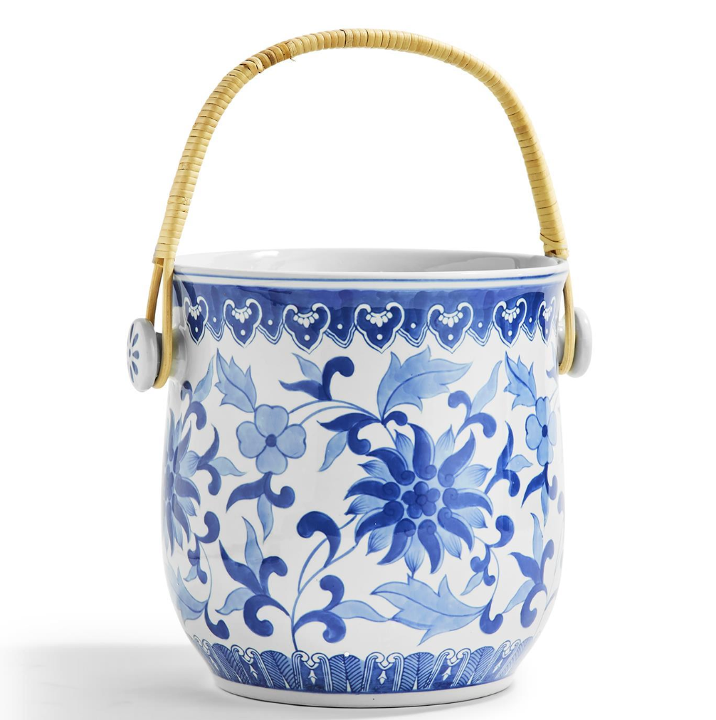 Ceramic ice bucket with blue floral pattern and wicker handle on a white background