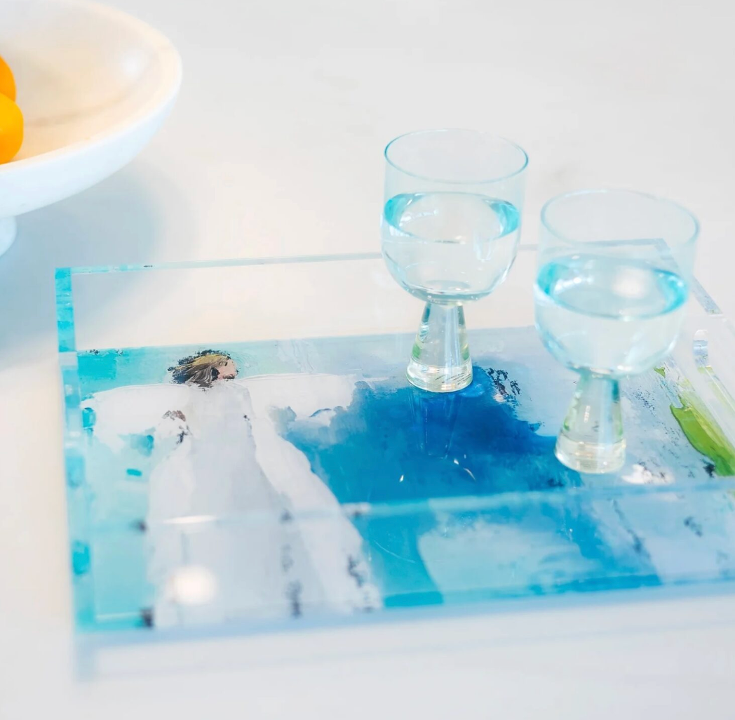 Two glasses of water on a turquoise blue and white acrylic tray with watercolor angel  with a scenic print and white background
