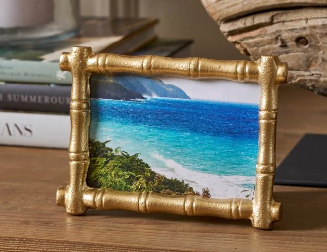 Gold bamboo-style picture frame with a beach photo on a wooden surface