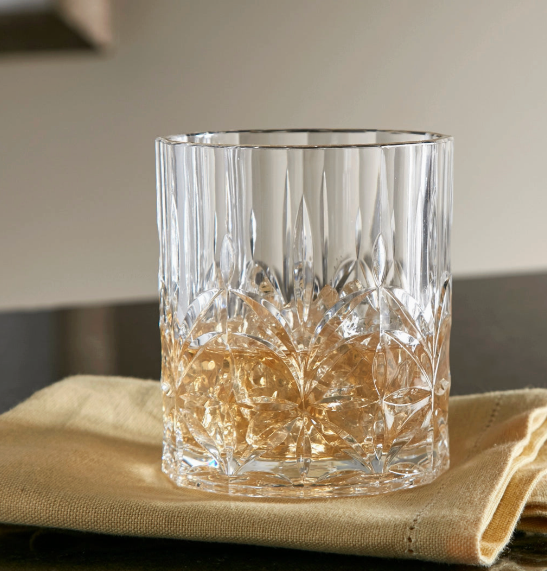 Royal Carved Low Ball Glass by Huang Acrylic — acrylic rocks glass with decorative carved pattern resting on a folded beige cloth over a dark surface.etric