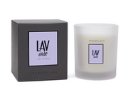 An Archipelago soy candle in a frosted glass jar next to its dark gray packaging box. Both the jar and the box feature a lavender square label with the text 'LAV aNde' and 'ARCHIPELAGO'.