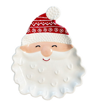 A ceramic Santa Claus face plate or tray with a red patterned hat, peach-toned cheeks and nose, and a white textured beard on a plain white background.