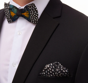 Silk Brackish brand scarf for pocket square with guinea feather black, white design in suit pocket with black jacket, white shirt and colorful bow tie on white background