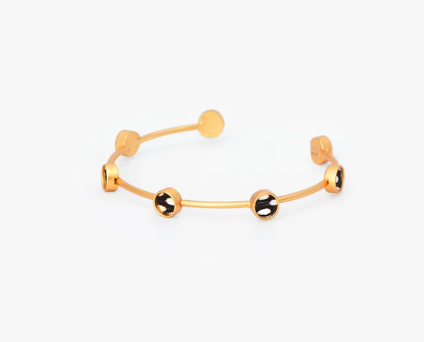 Brackish brand Gold cuff bracelet with black and white feather round insets on white background