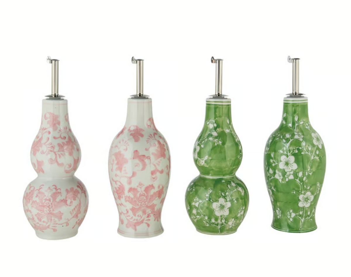 Four floral hand-painted stoneware oil cruets in pink and green, showing oval and double-gourd shapes with stainless steel pour spouts.