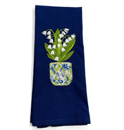A navy kitchen towel with a floral design of lilies of the valley in a chinoiserie planter pot embroidered in white and green colors.
