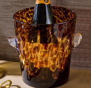 Bottle of champagne in a glass tortoise shell print ice bucket on a textured surface