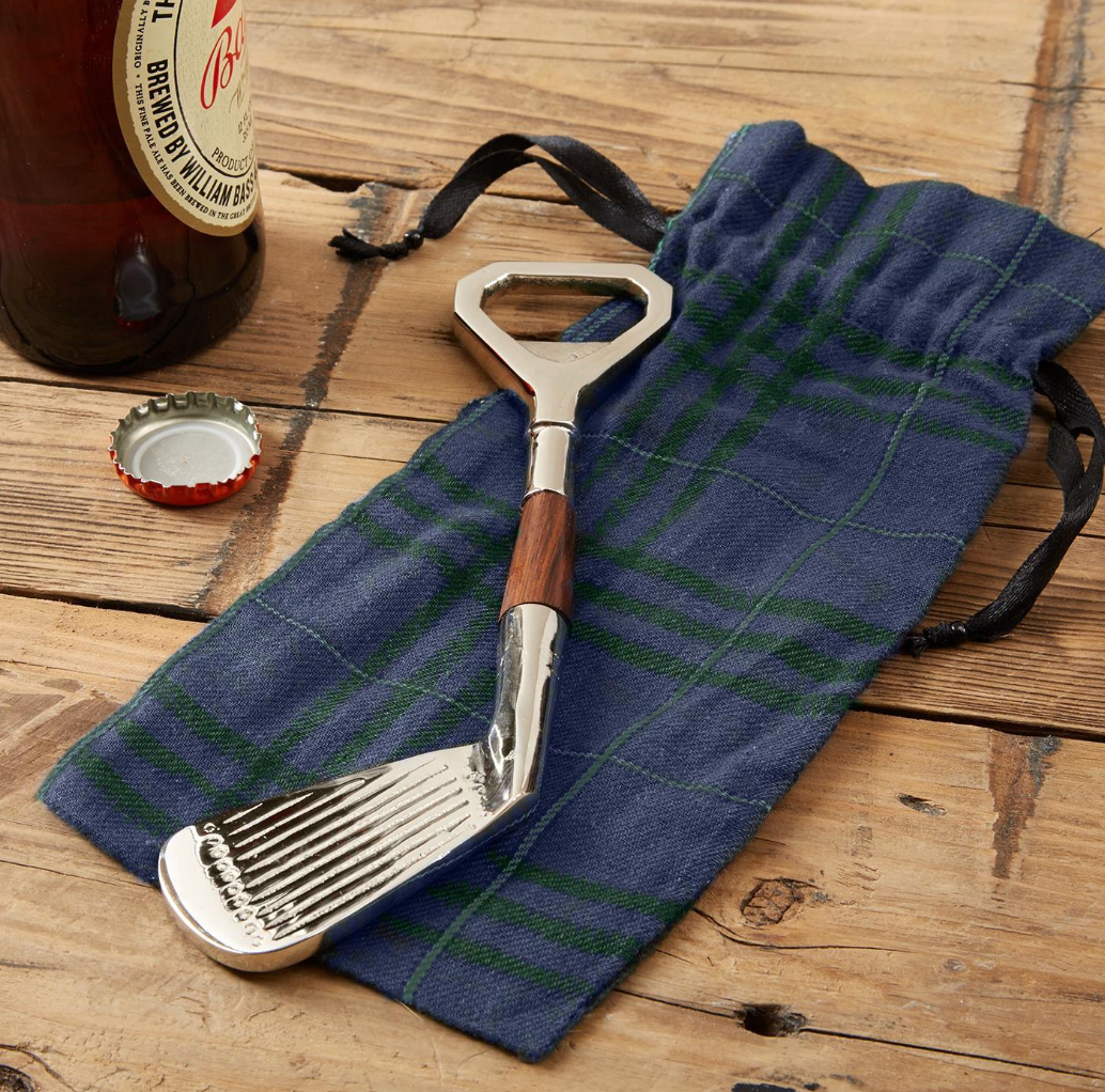 Golf club shaped bottle opener on dark plaid sack sitting on wood table