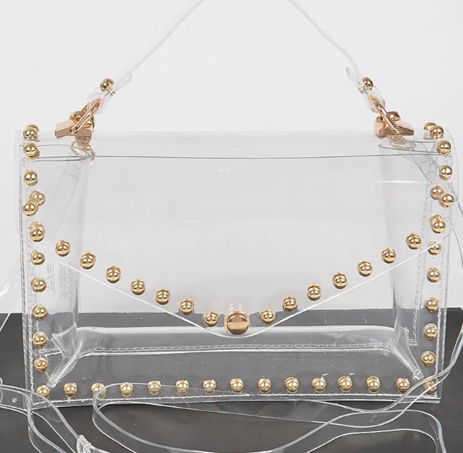 Clear bag with gold studs and gold hardware on white background