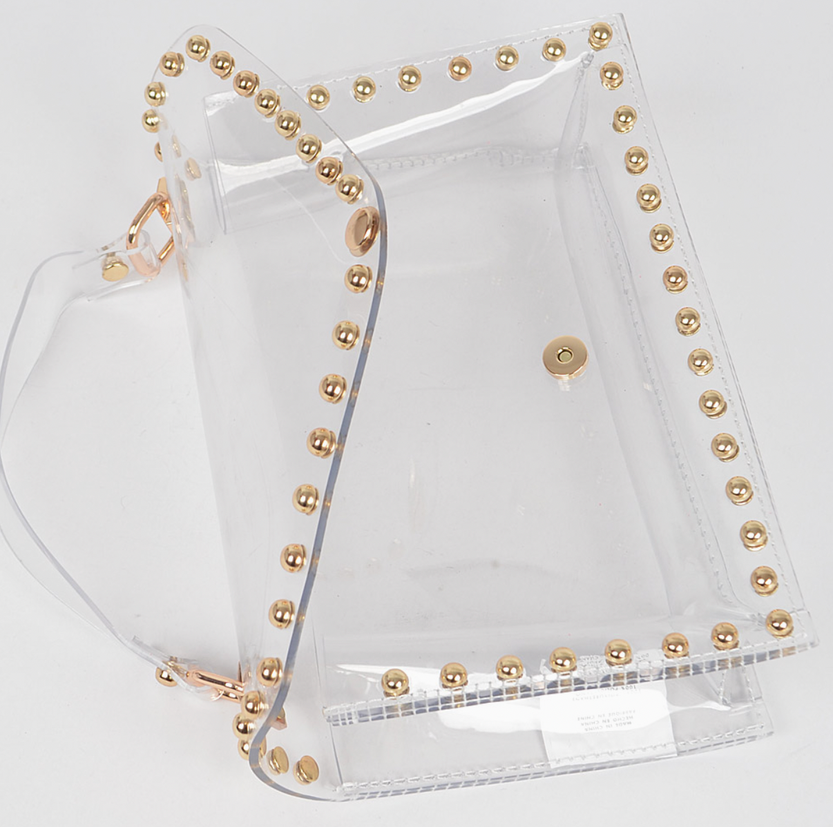 Clear bag with gold studs and gold hardware on white background