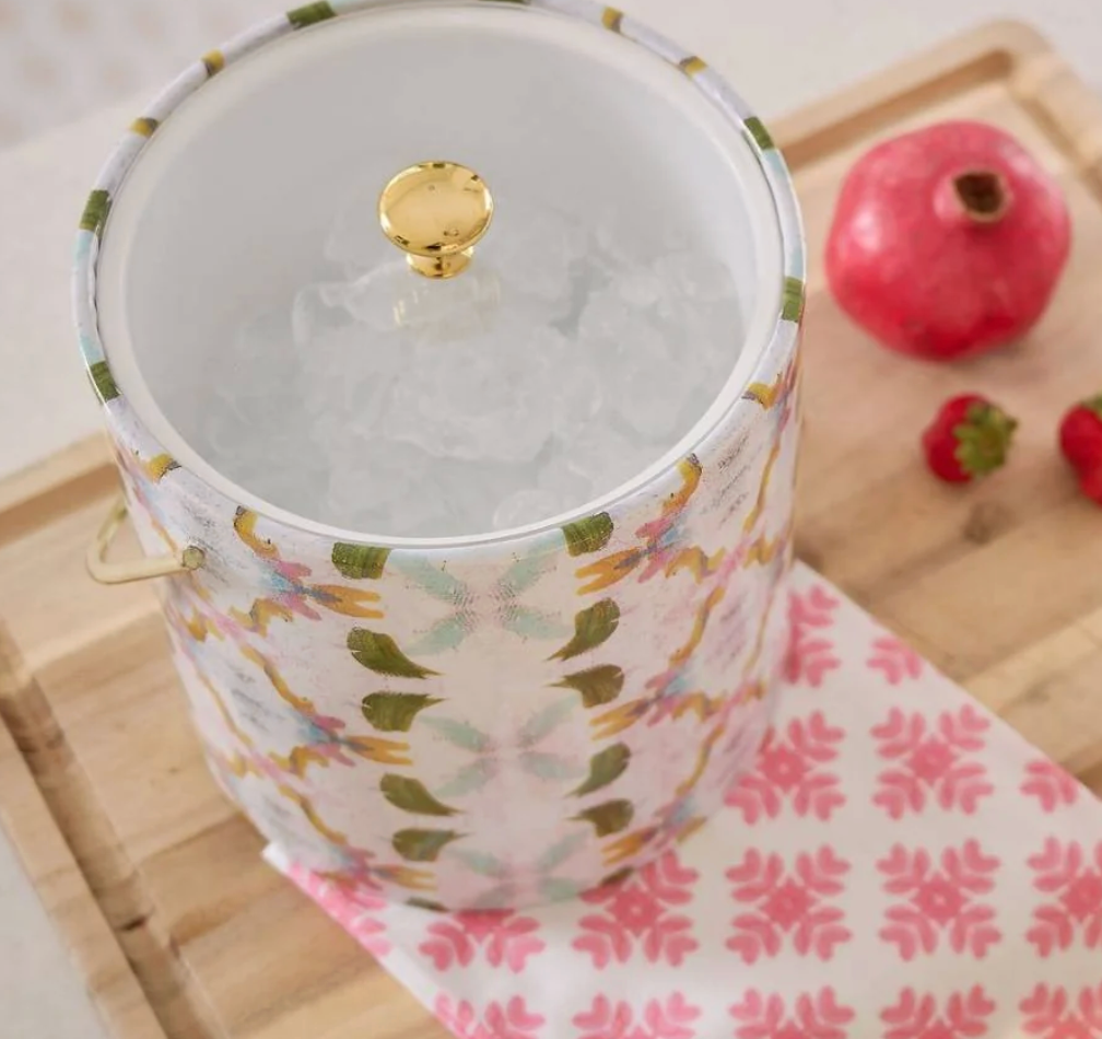 Laura Park Dogwood Ice Bucket with floral pattern on a wooden surface with pomegranate and strawberry.