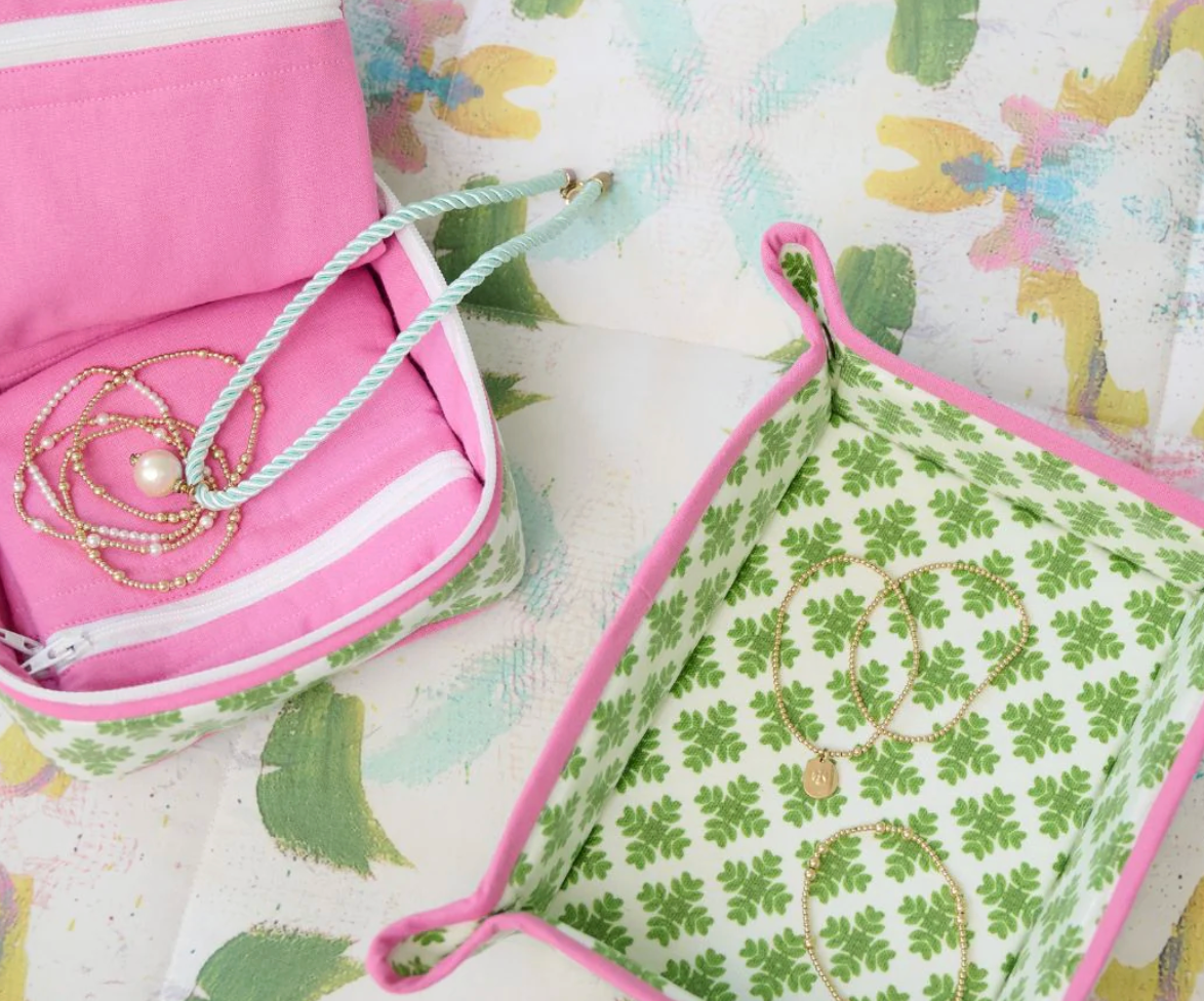 Laura Park Brushstrokes Design Fabric waxed cotton snap tray with green floral pattern on a light surface and a pink jewelry box on floral cloth